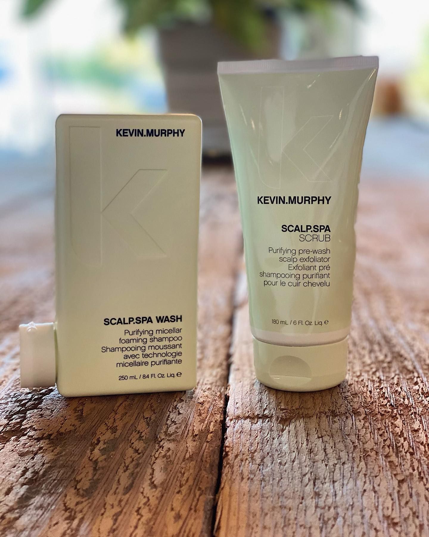 Two bottles of hair products are sitting on a wooden table.