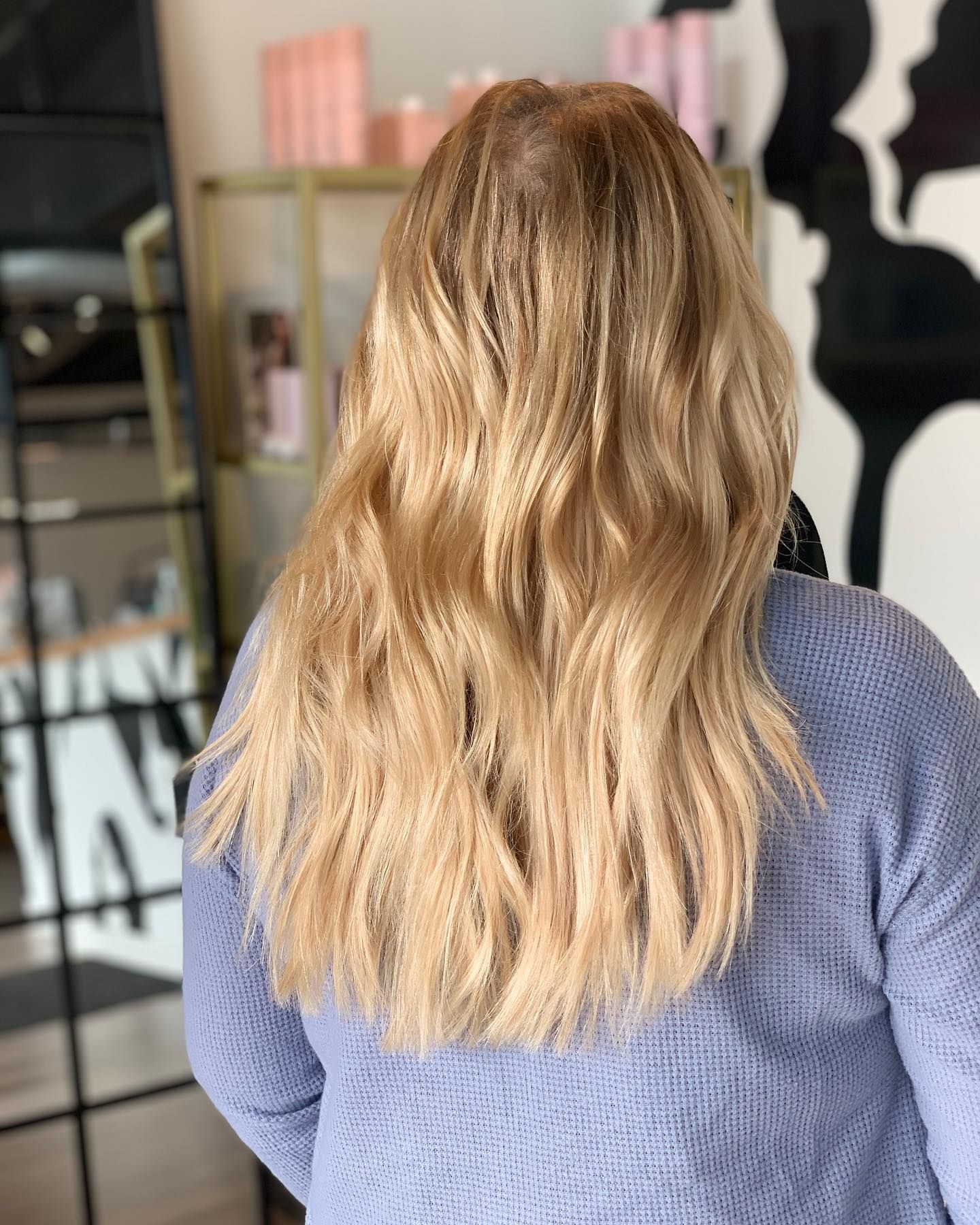 A woman with long blonde hair is wearing a blue sweater.