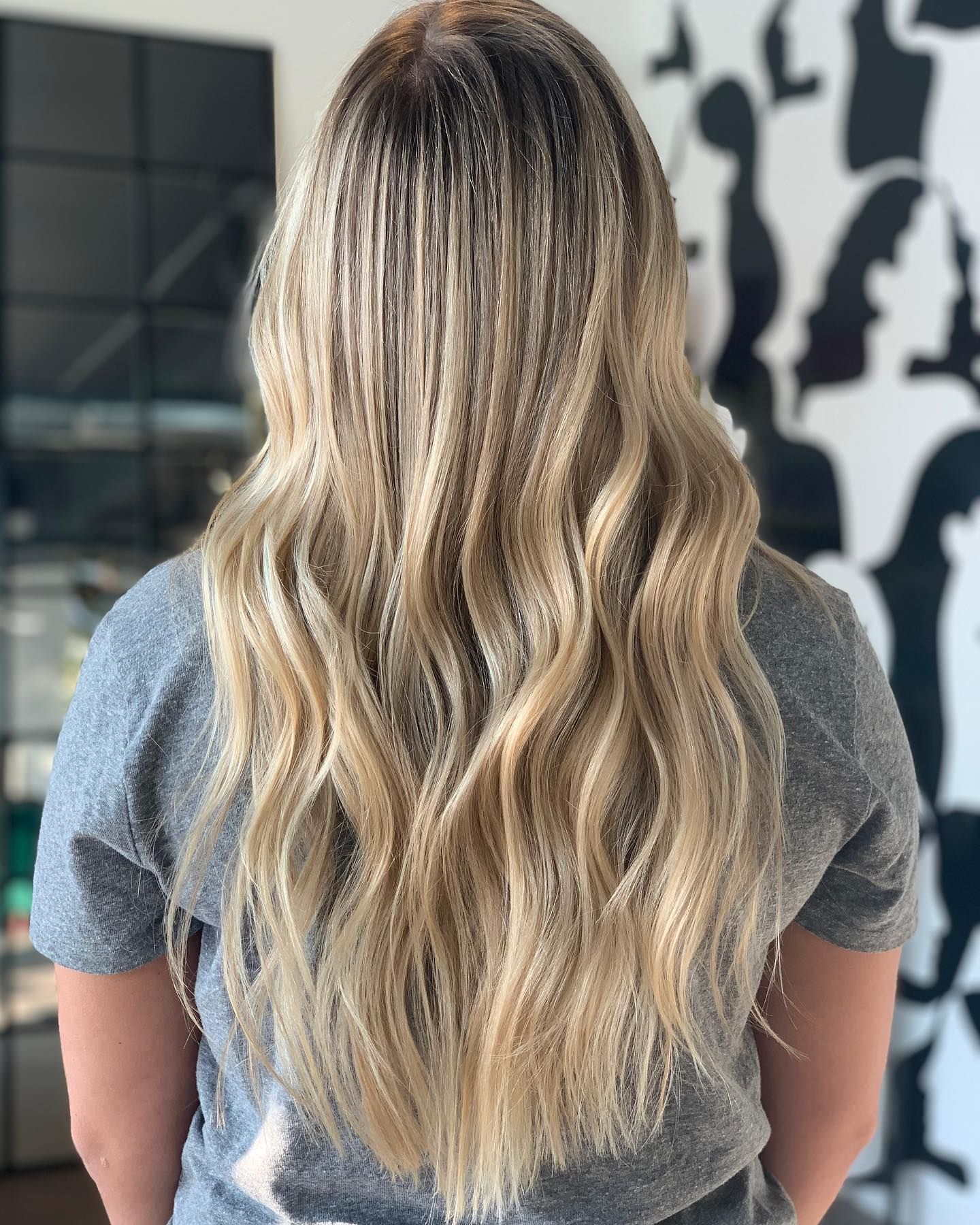 A woman with long blonde hair is wearing a grey shirt.