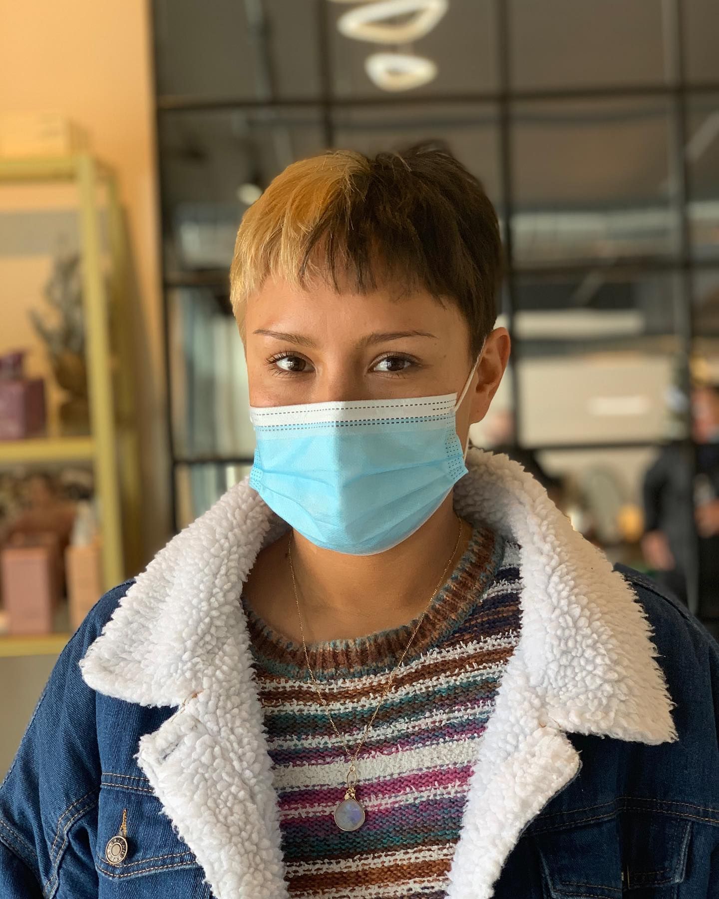 A woman wearing a face mask and a denim jacket.