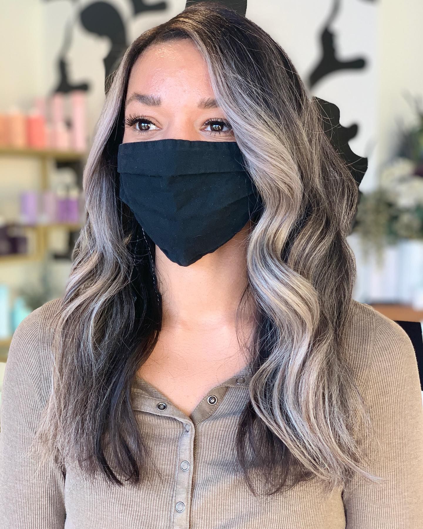 A woman with long hair is wearing a black face mask.