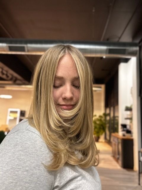 Two-story house with gray siding, a dark roof, and a two-car garage. Wet pavement reflects the colorful sunset.