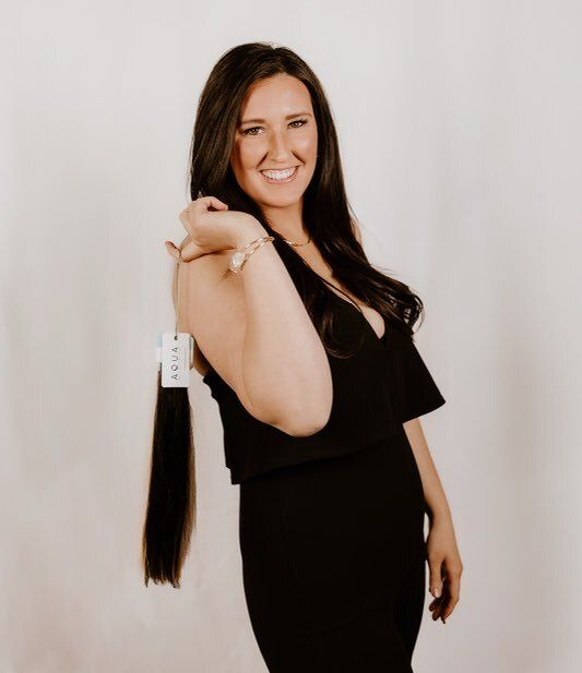 A woman is wearing a denim jacket and smiling.