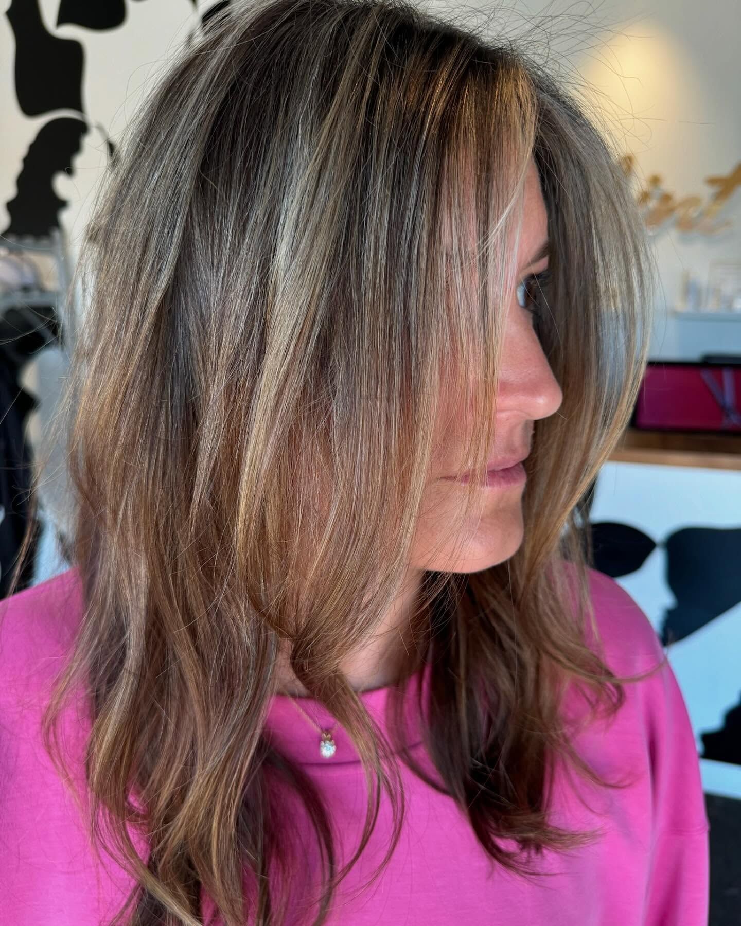 A woman with long brown hair is wearing a pink sweater.