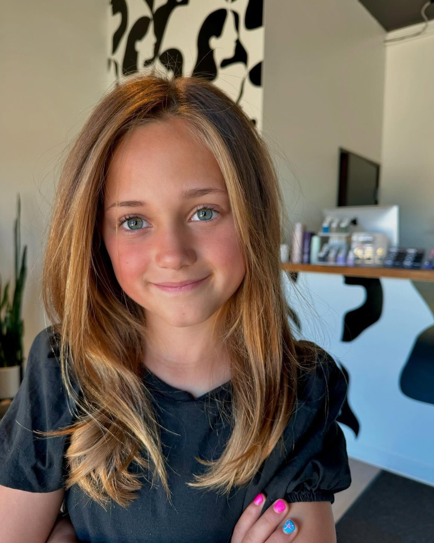 A young girl with long hair is standing in a room with her arms crossed.