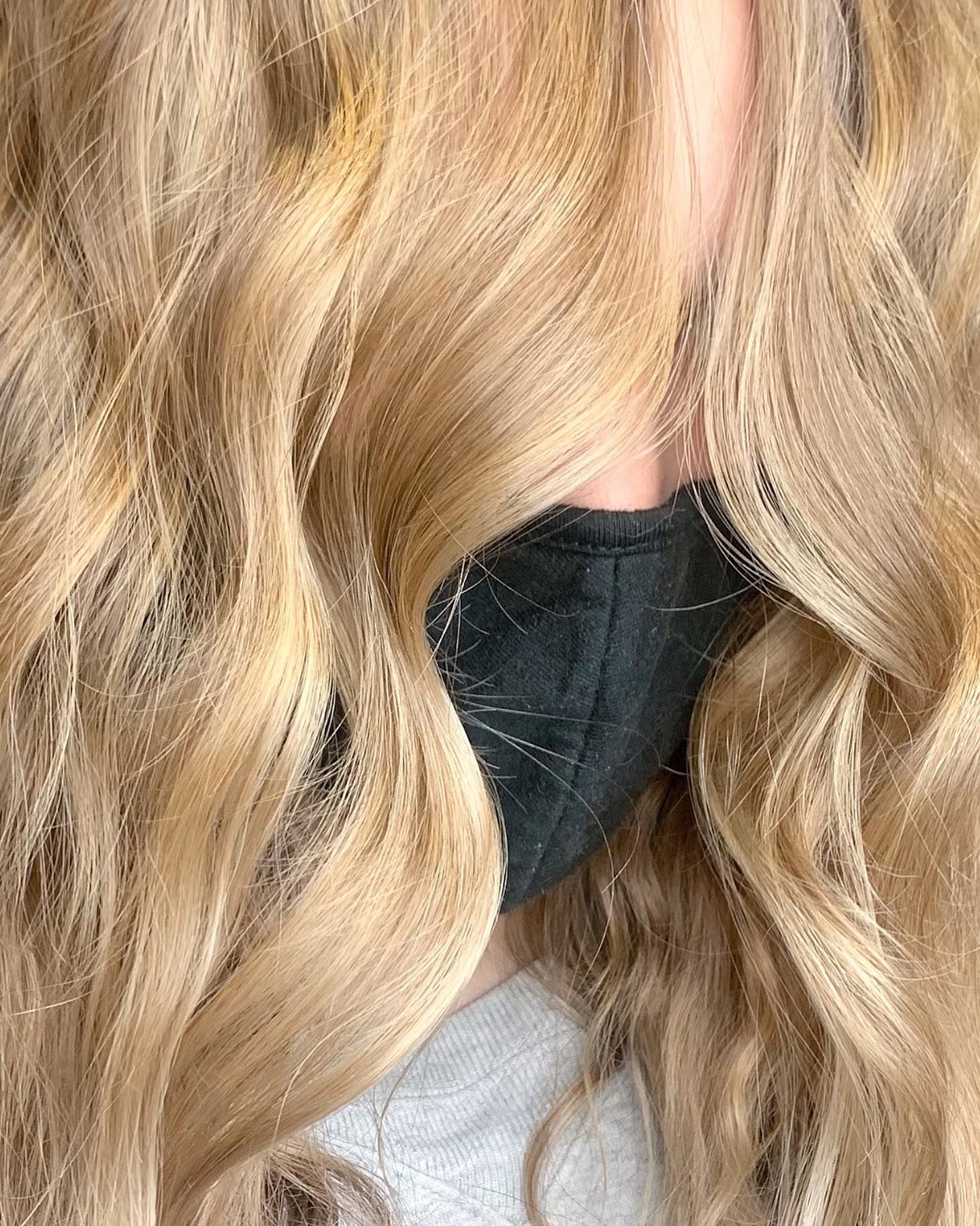 A woman with long blonde hair wearing a black mask.