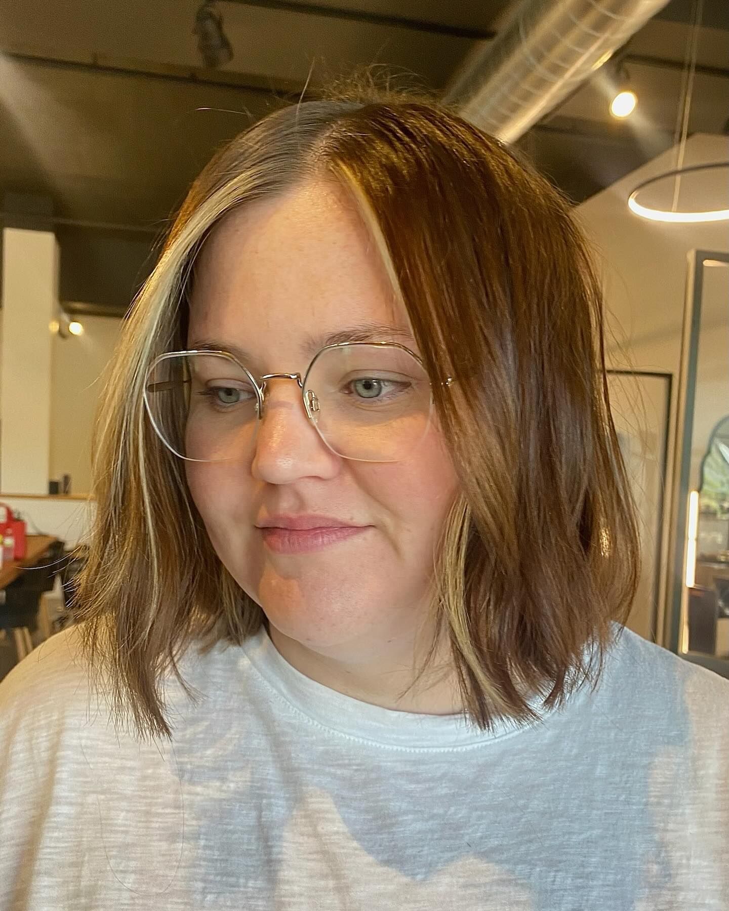 A woman wearing glasses and a white shirt is looking at the camera.