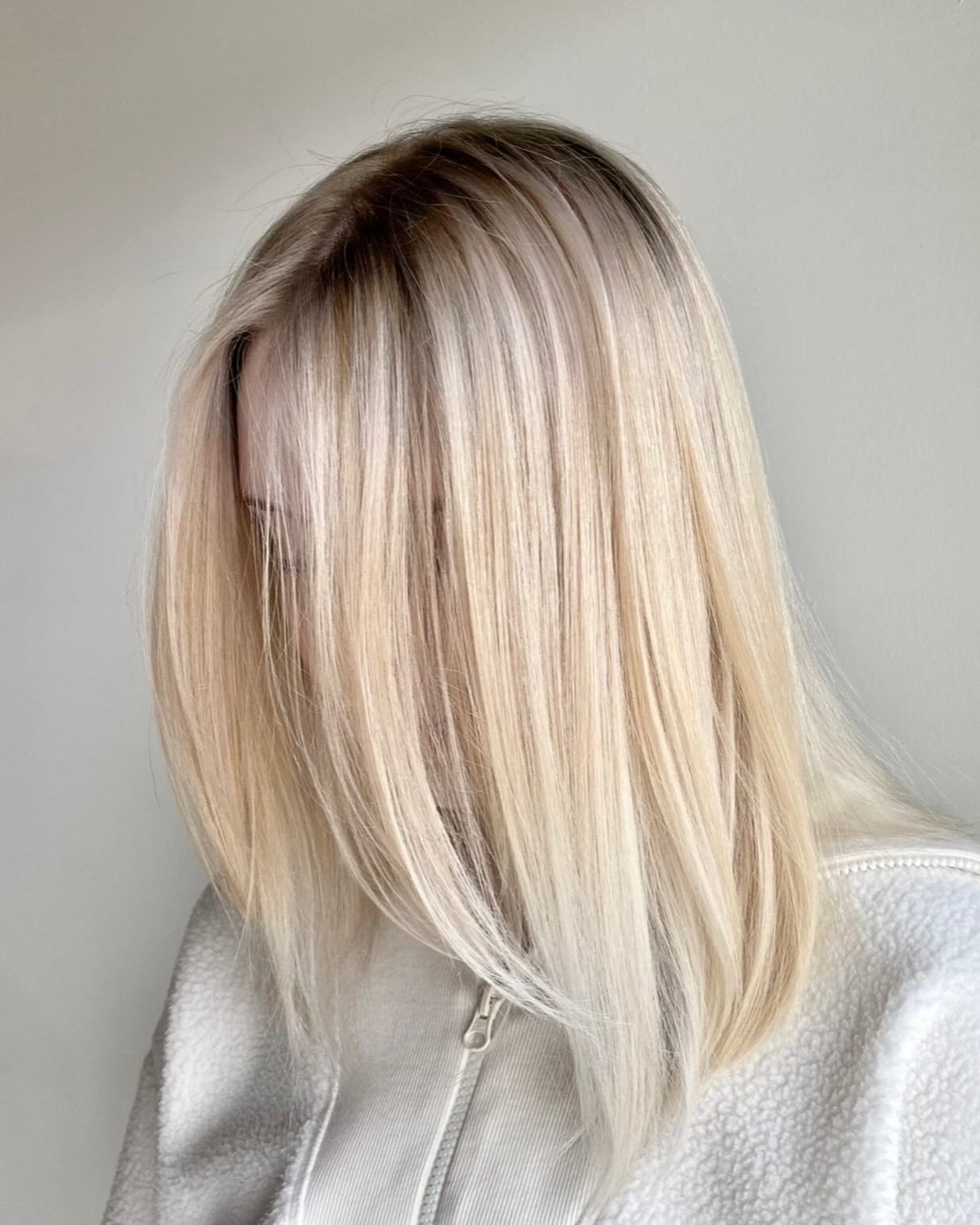 A woman with blonde hair is covering her face with her hair.