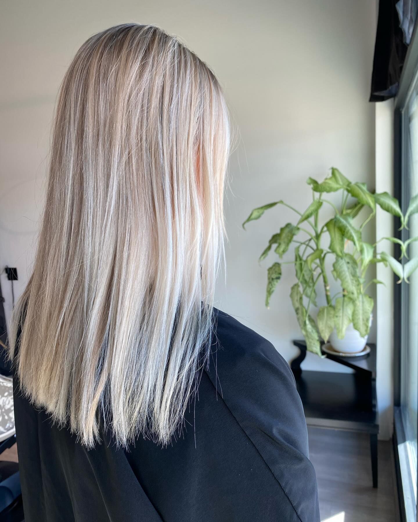 A woman with long blonde hair is looking out a window