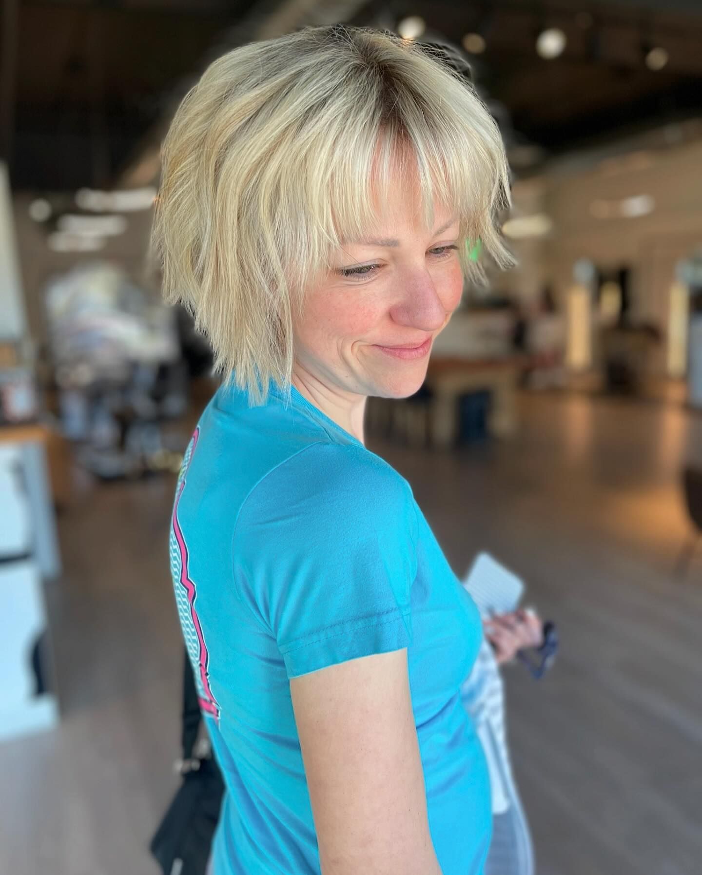 A woman with blonde hair and a blue shirt is standing in a room.