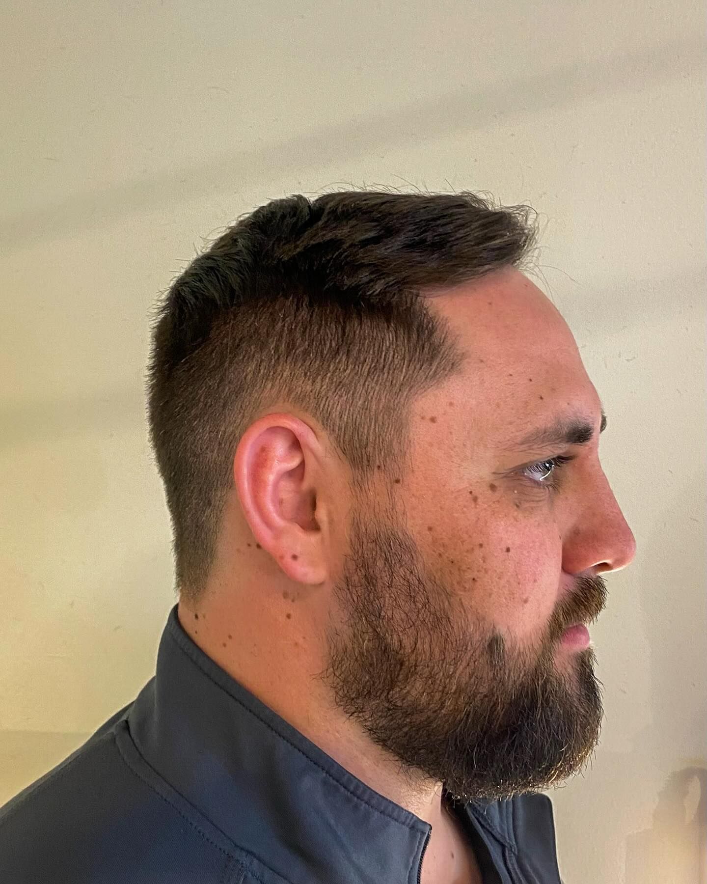 A man with a beard and short hair is standing in a room.