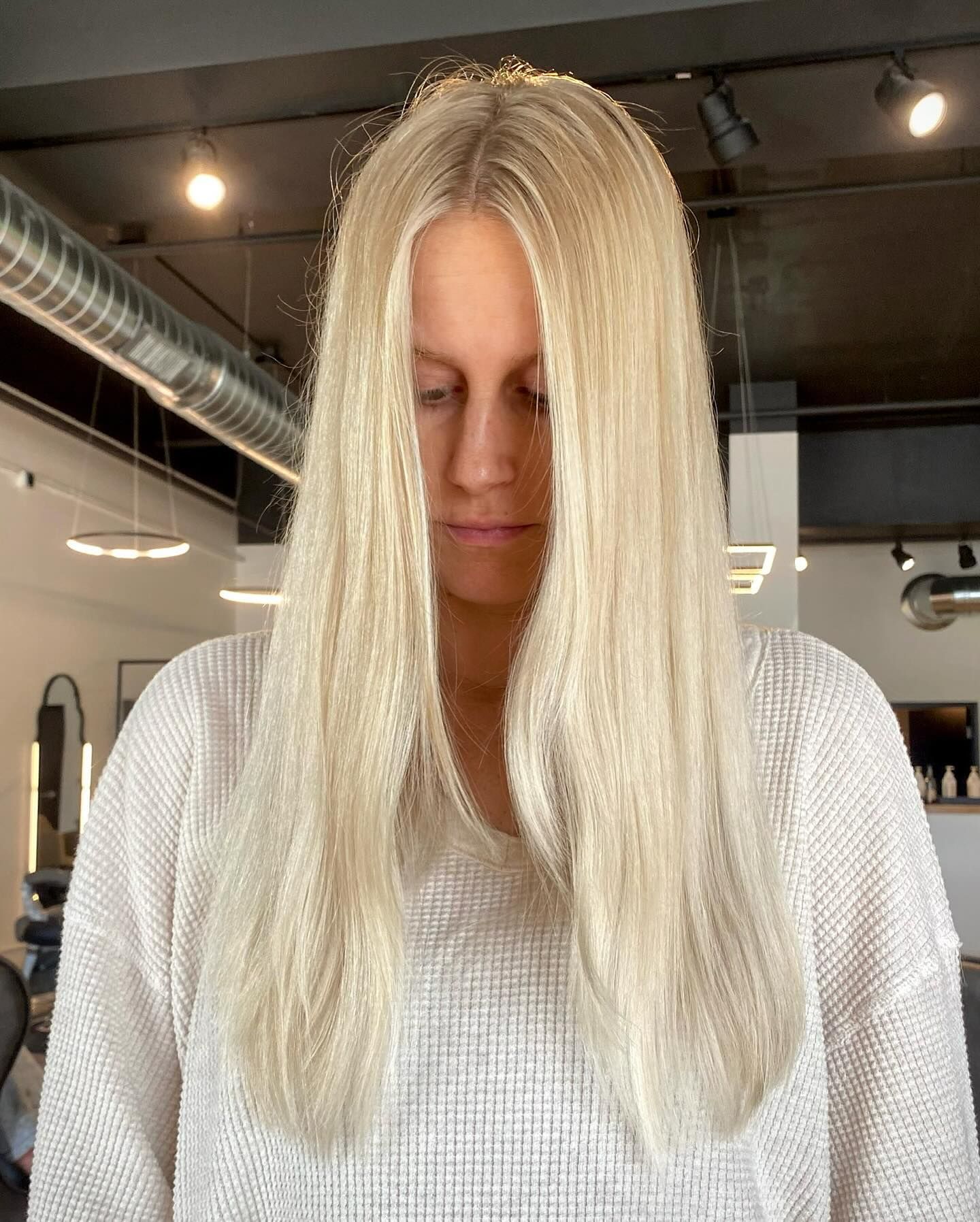 A woman with blonde hair is wearing a white sweater