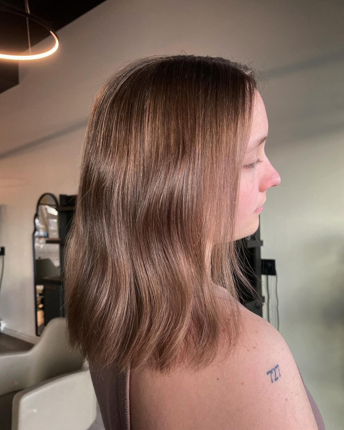 A woman with long hair and a tattoo on her arm is standing in a room.
