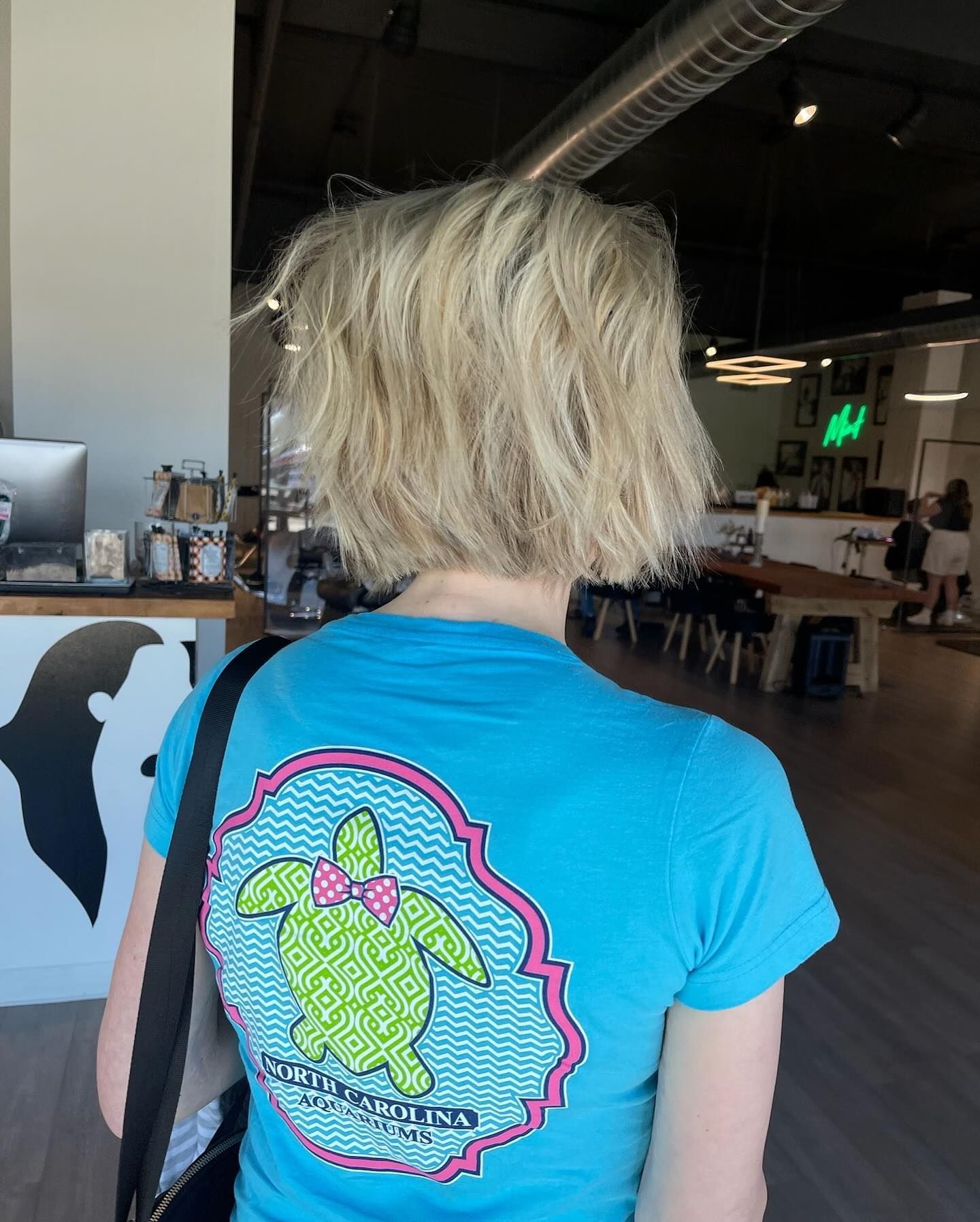 A woman wearing a blue shirt with a turtle on the back