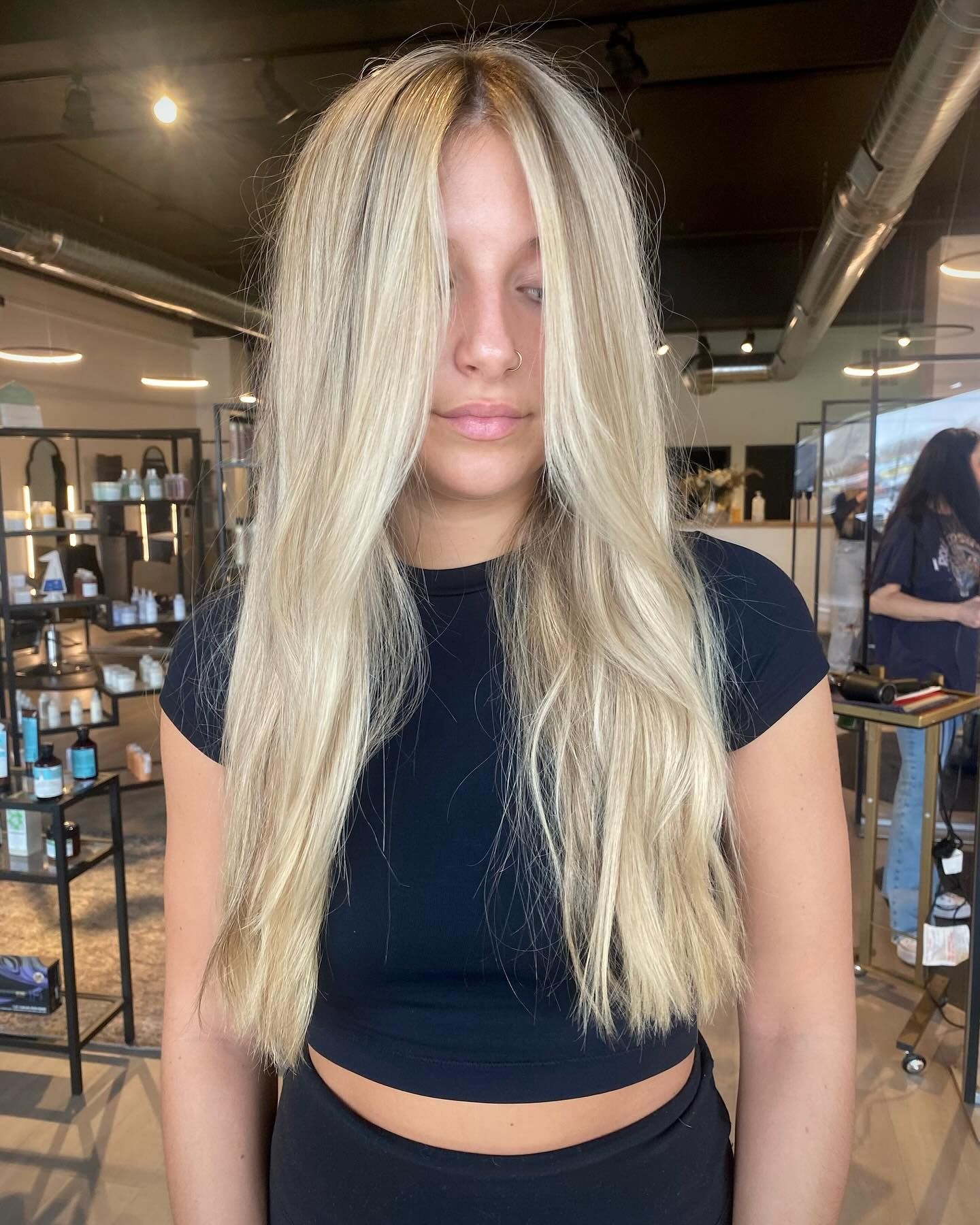 A woman with long blonde hair is wearing a black crop top and black pants.