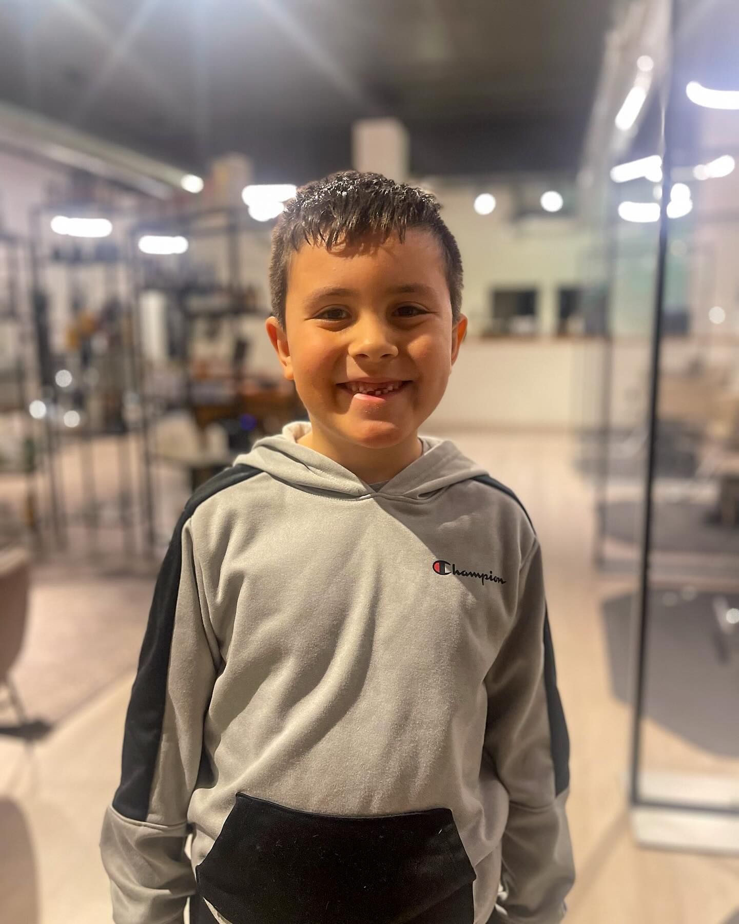 A young boy wearing a champion hoodie is smiling for the camera.