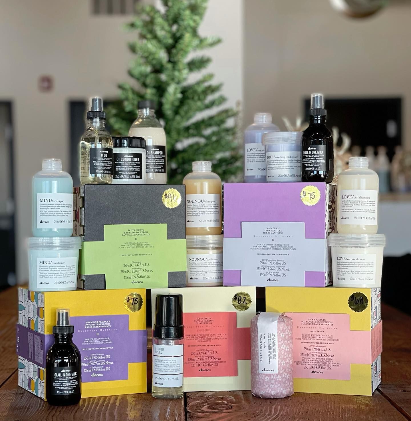 A bunch of bottles and boxes on a table with a christmas tree in the background