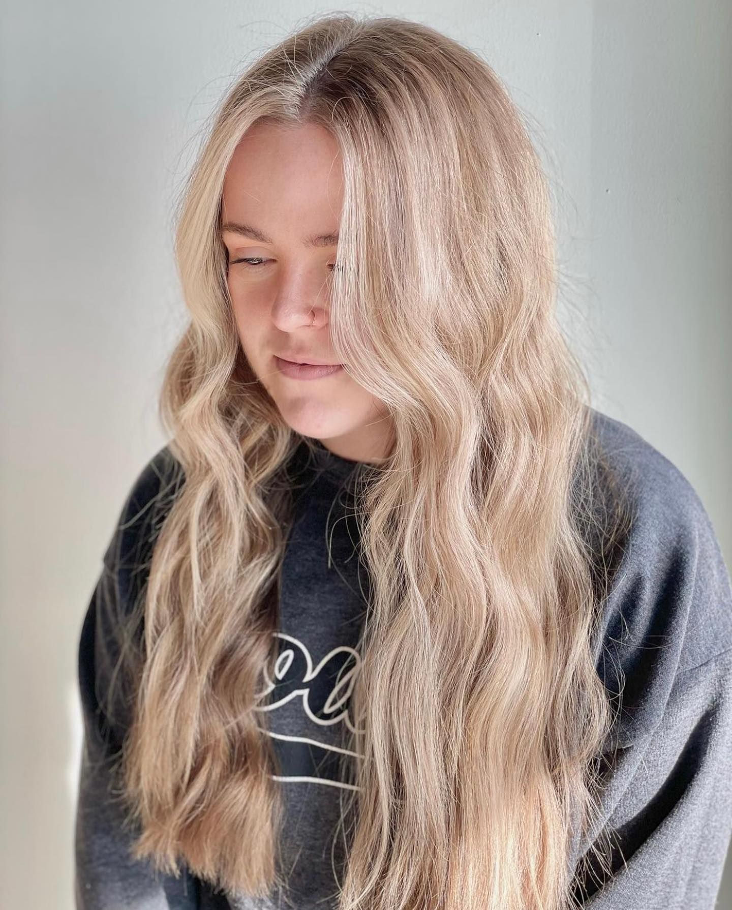 A woman with long blonde hair is wearing a gray sweatshirt.
