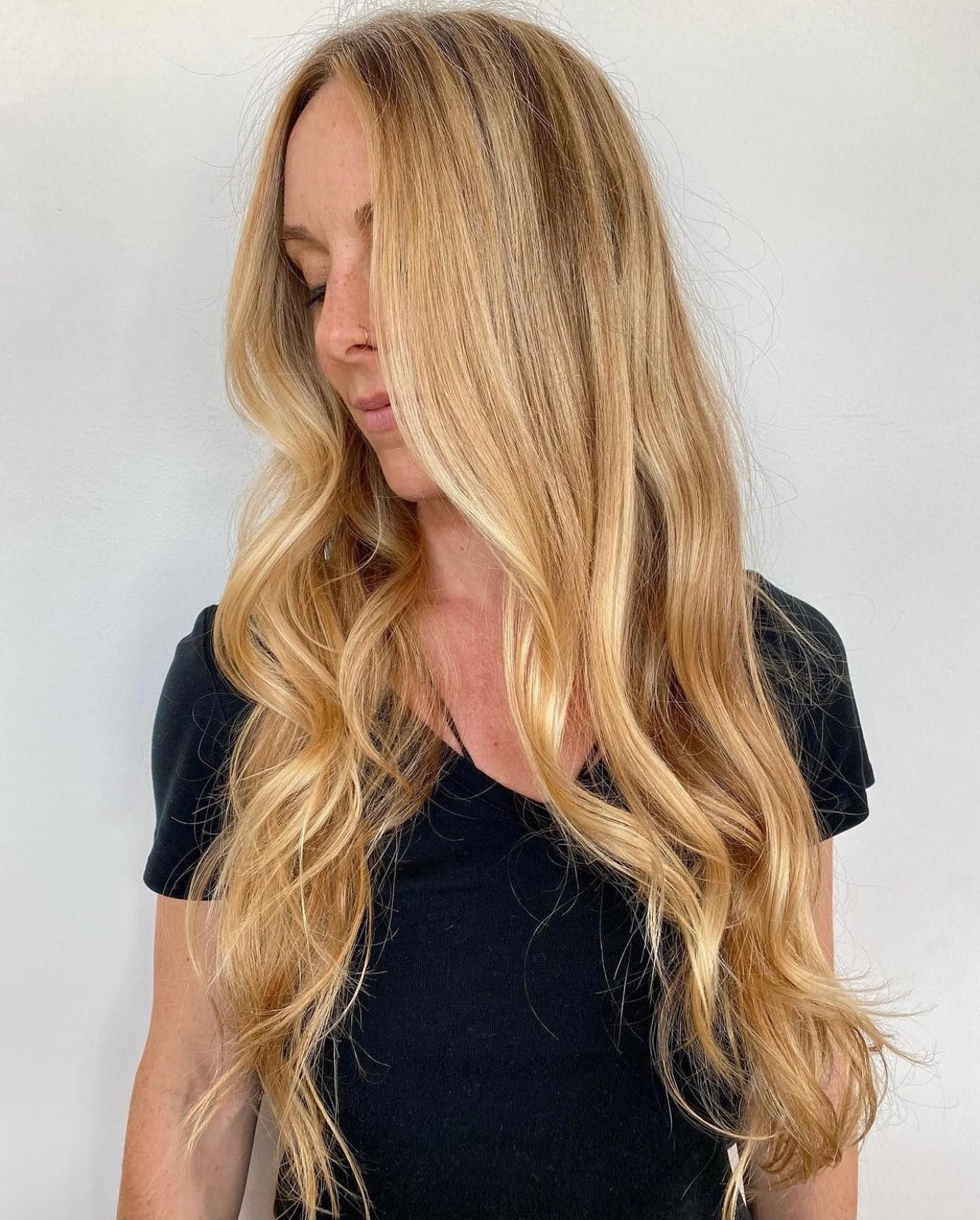 A woman with long blonde hair is wearing a black shirt.