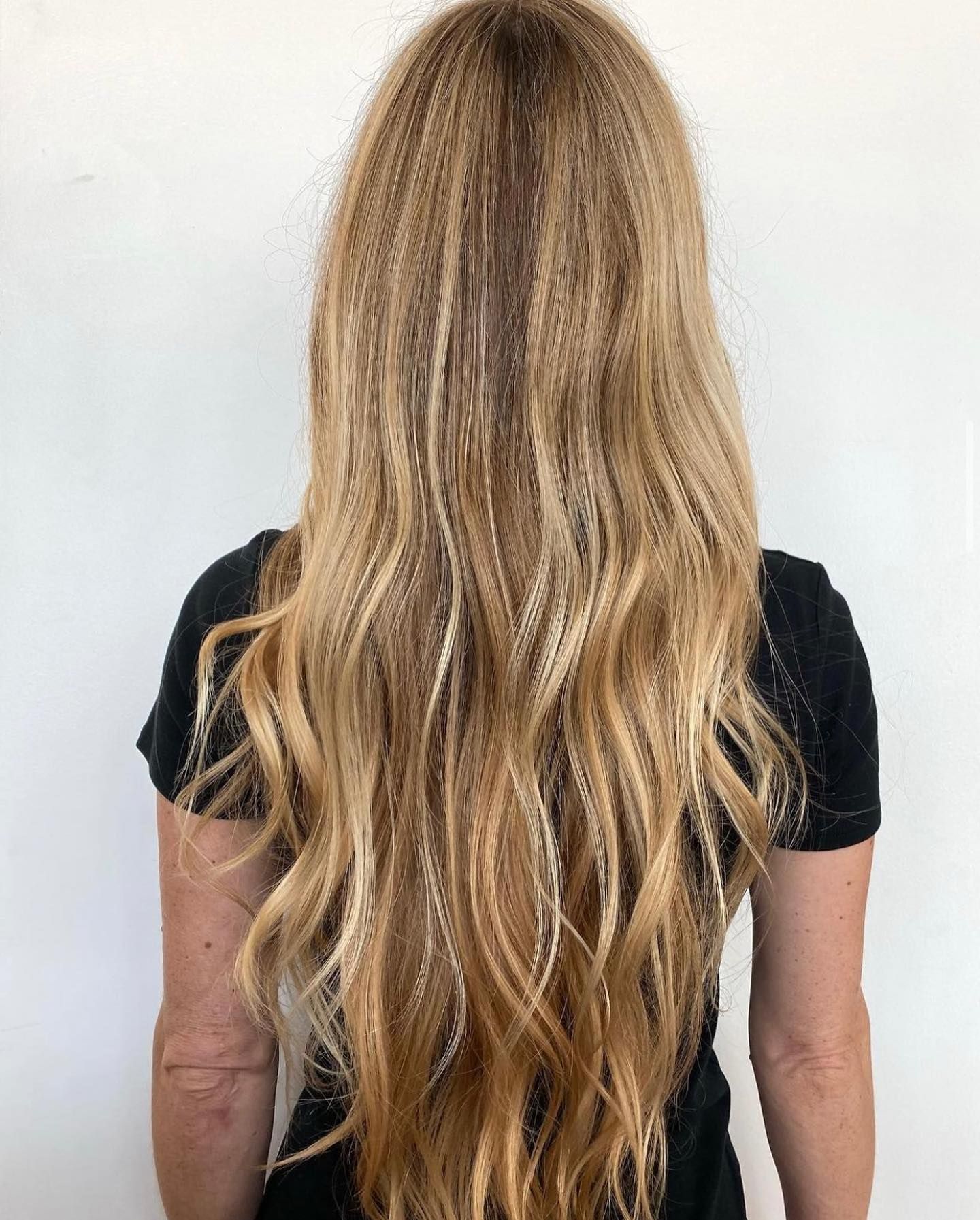 A woman with long blonde hair is wearing a black shirt.