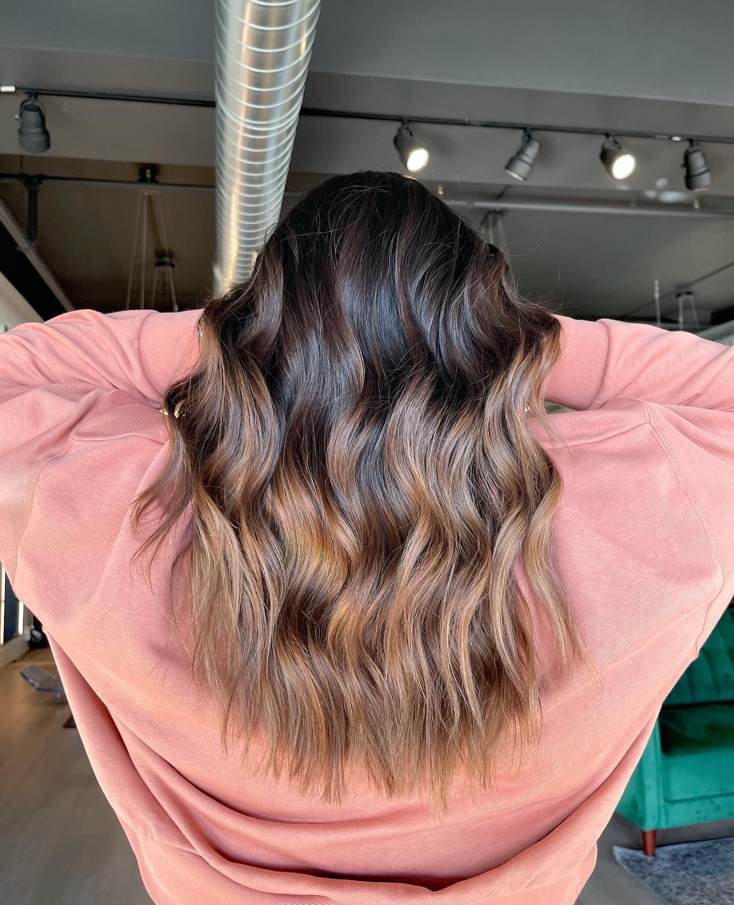 A woman in a pink sweater is standing with her arms outstretched.