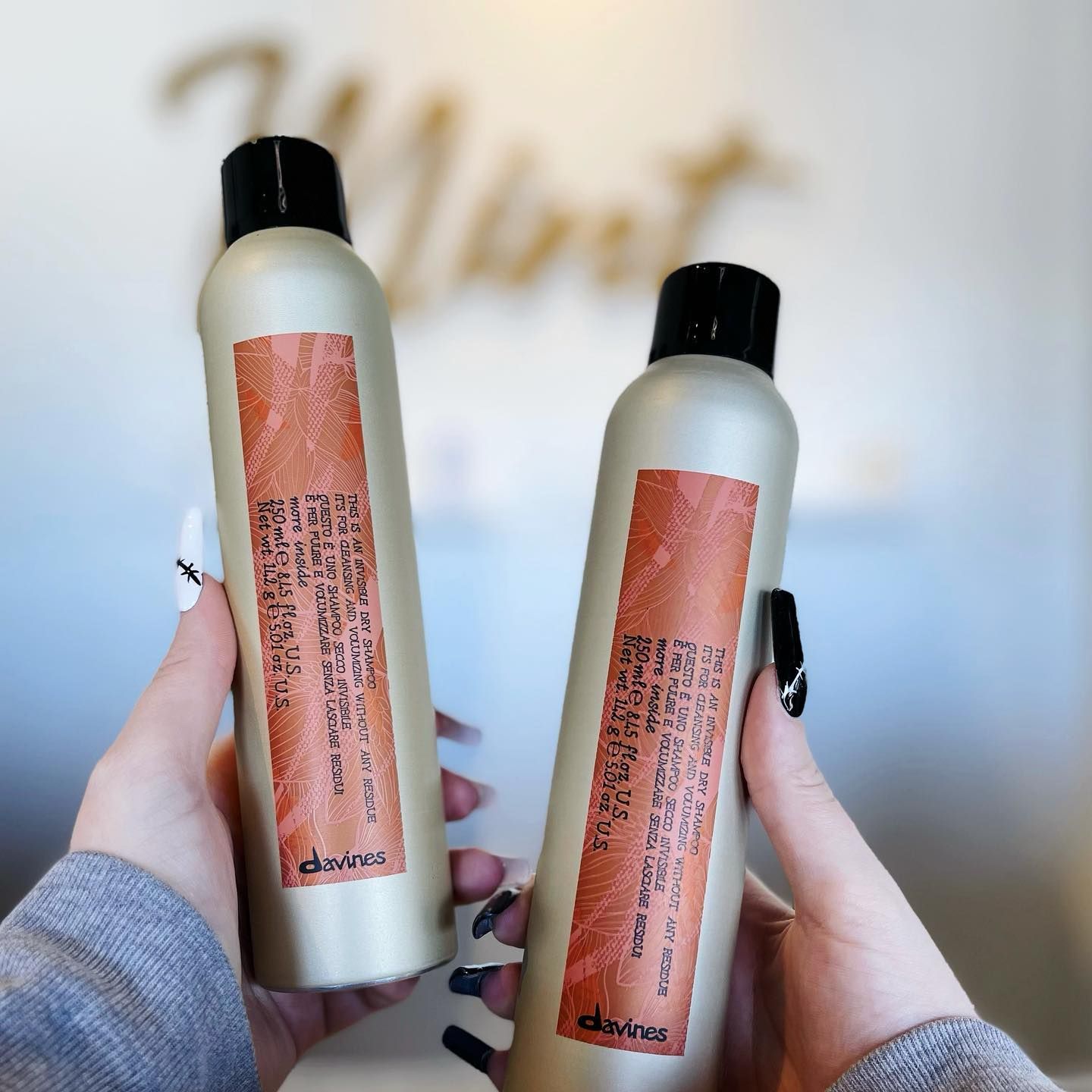 A person is holding two bottles of hair spray in their hands