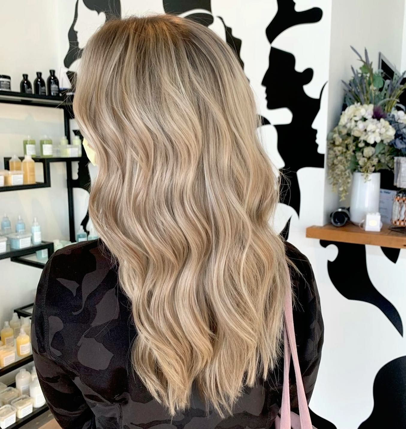 A woman with long blonde hair is standing in a salon