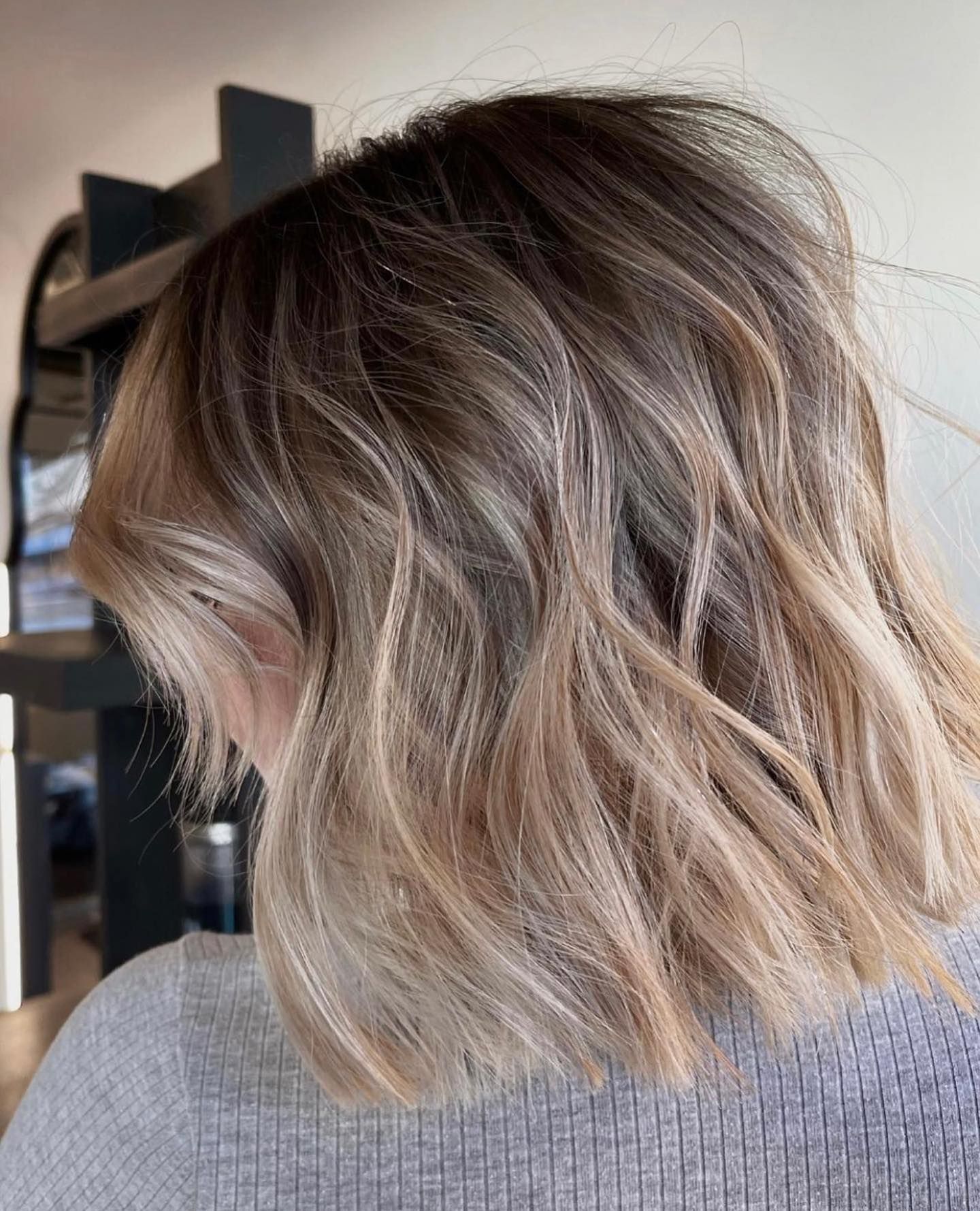 A woman with short blonde hair is wearing a grey sweater.