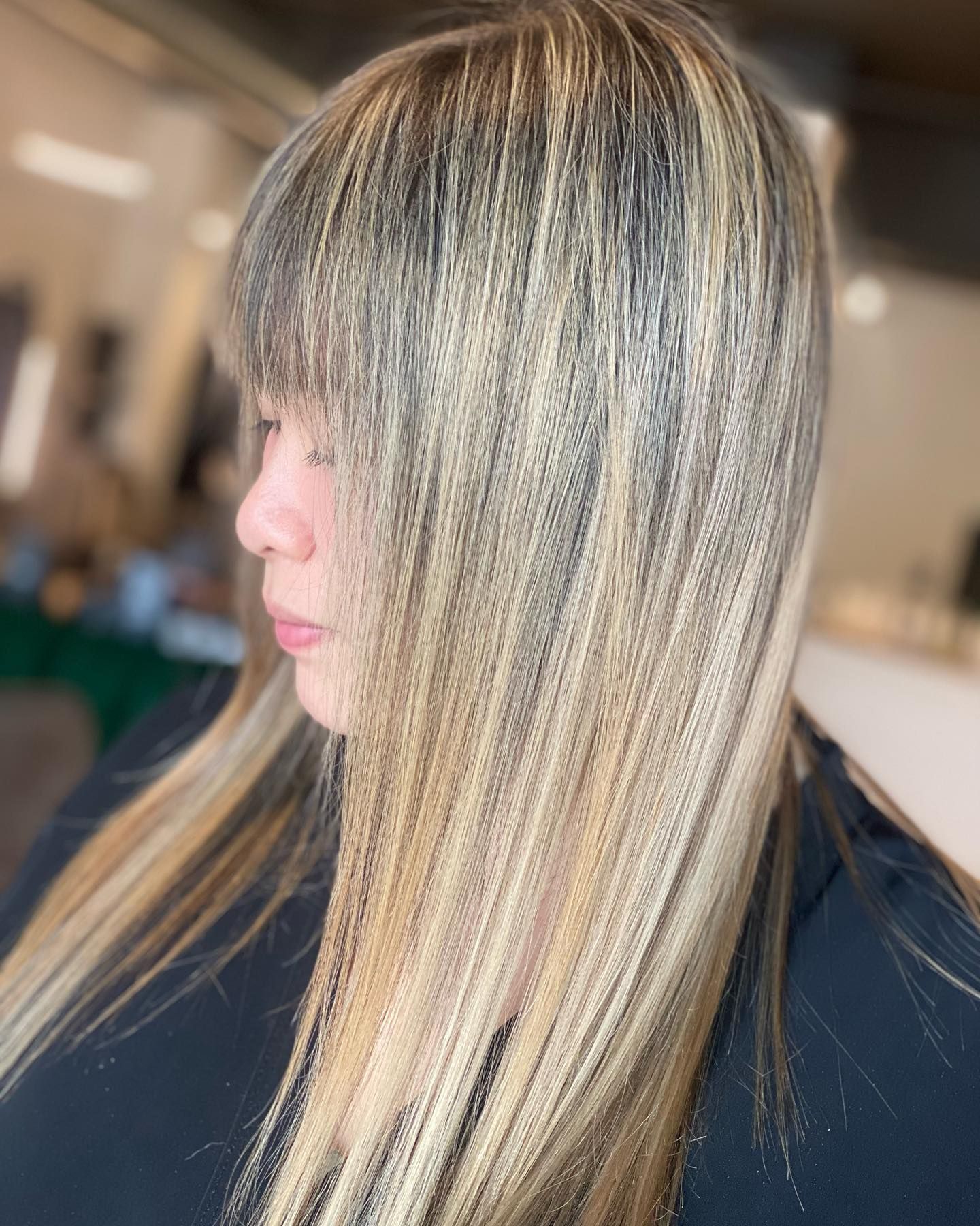 A woman with long blonde hair and bangs is wearing a black shirt.