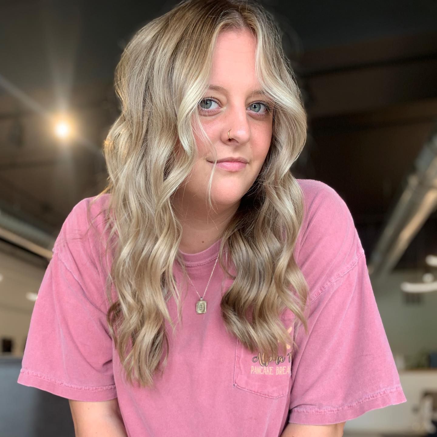 The woman is wearing a pink shirt and a necklace.