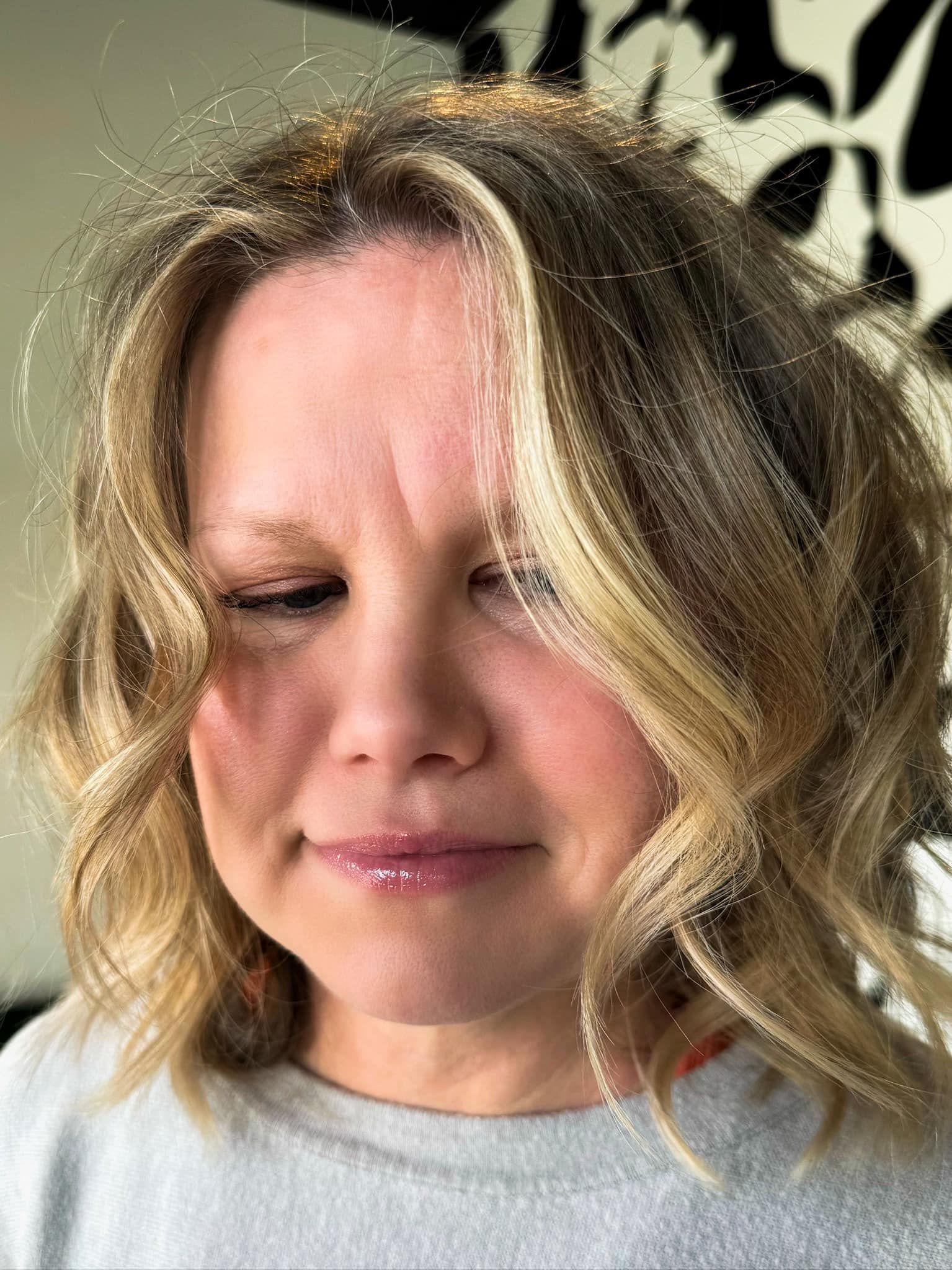 A woman with blonde hair and a gray shirt is making a funny face.