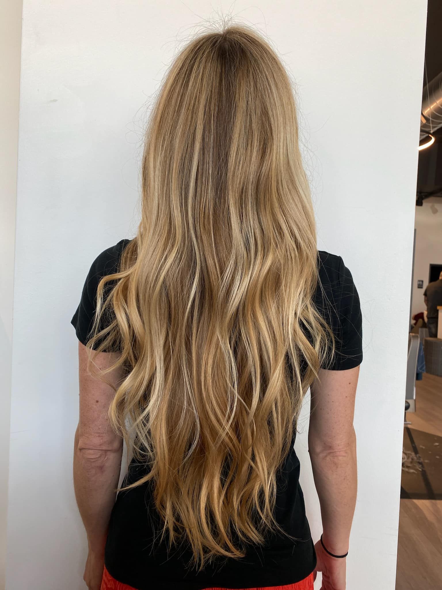 A woman with long blonde hair is wearing a black shirt and red pants.