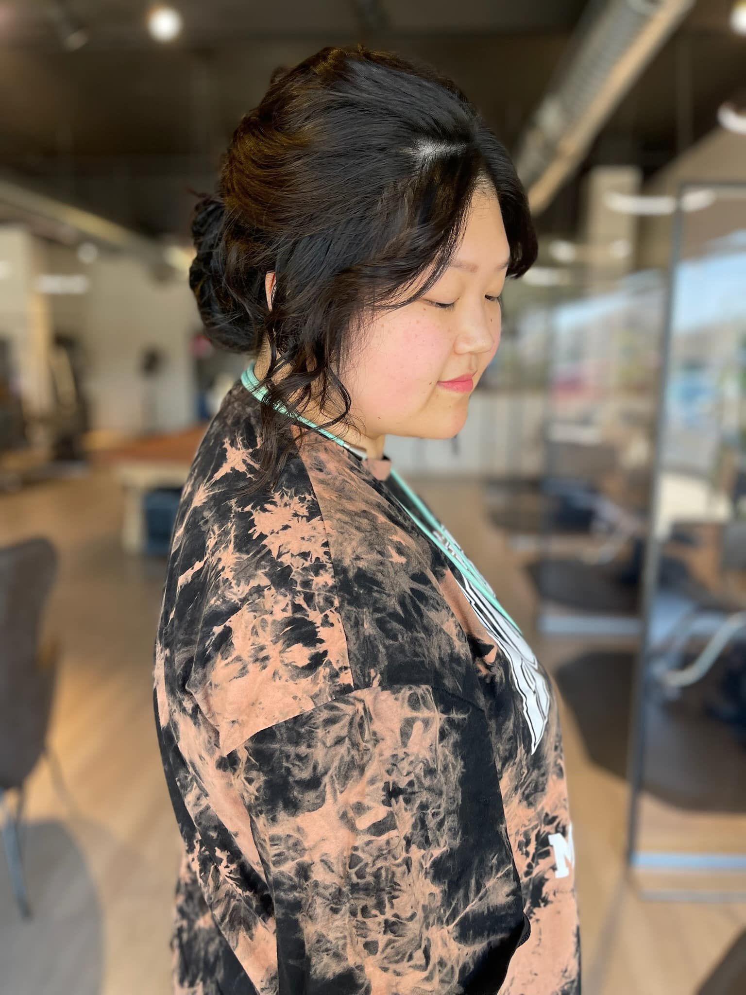 A woman is standing in a salon with her hair in a bun.