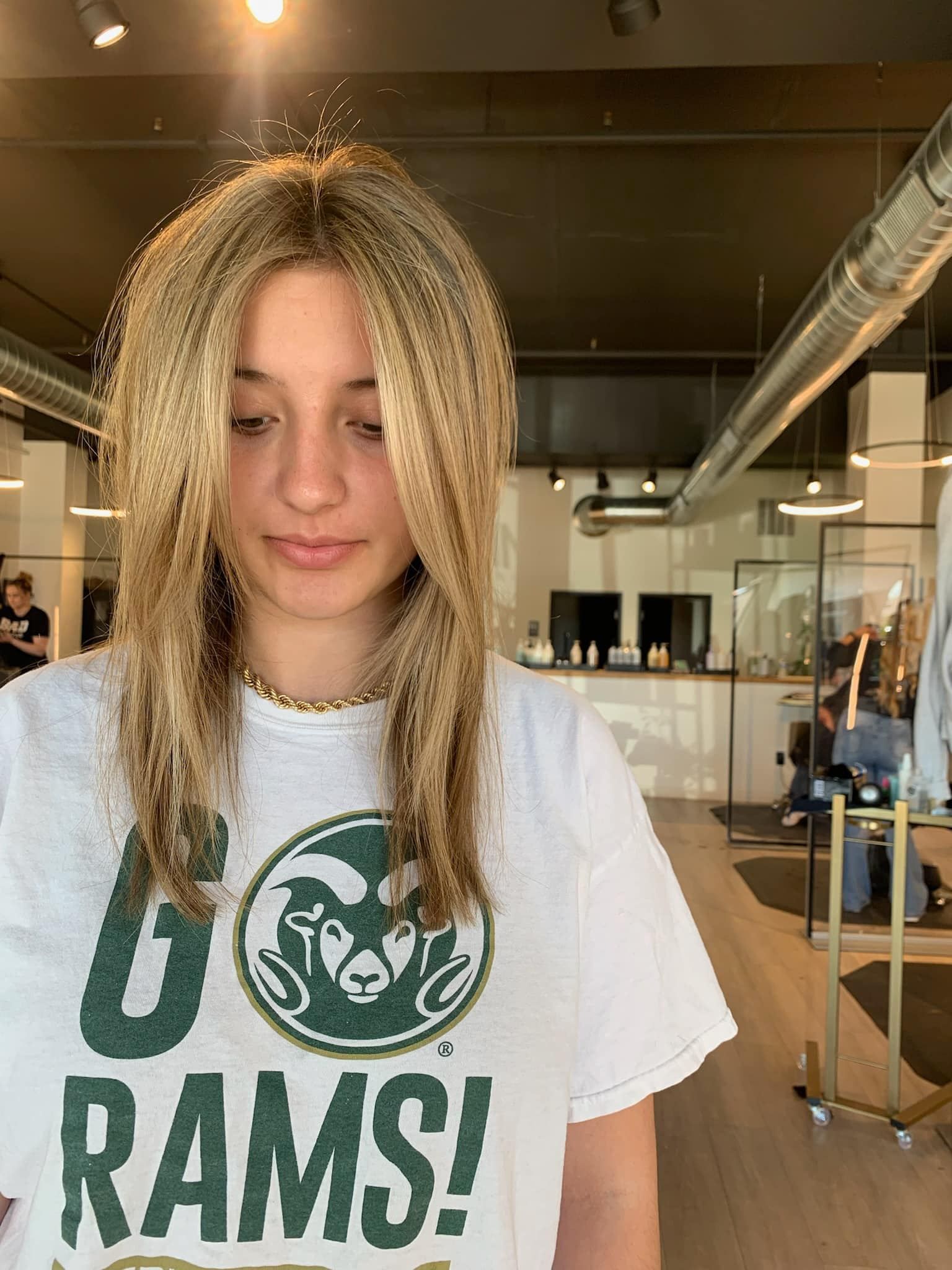 A woman wearing a rams t-shirt is standing in a room.