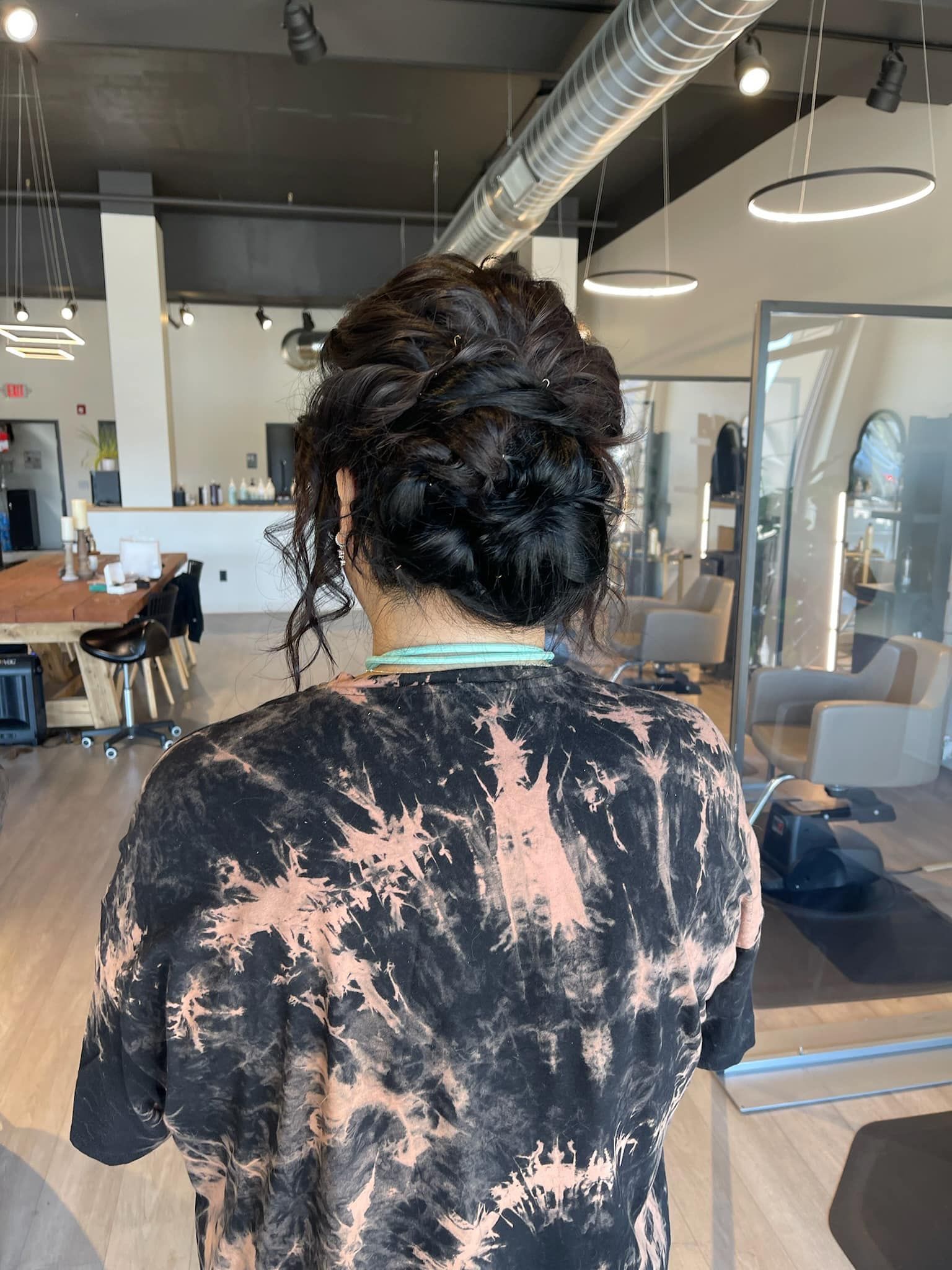 A woman is standing in a salon with her hair in a bun.