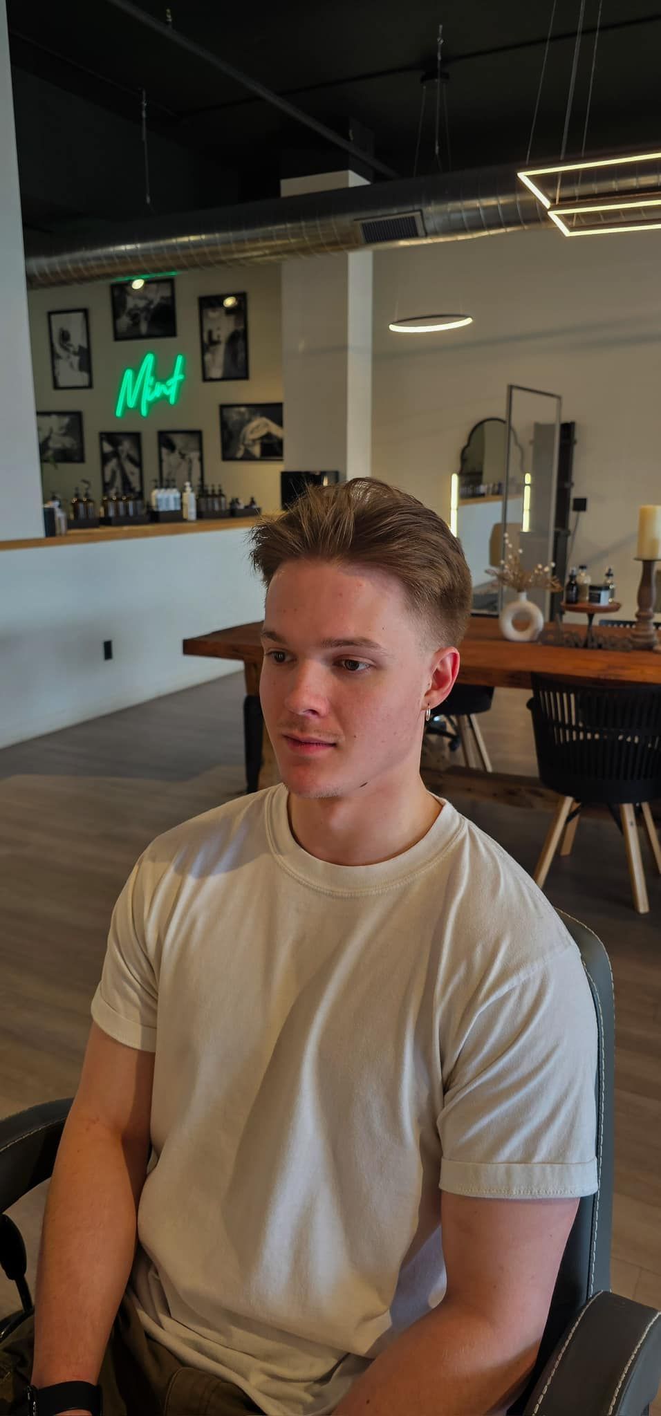 A young man is sitting in a chair in a barber shop.