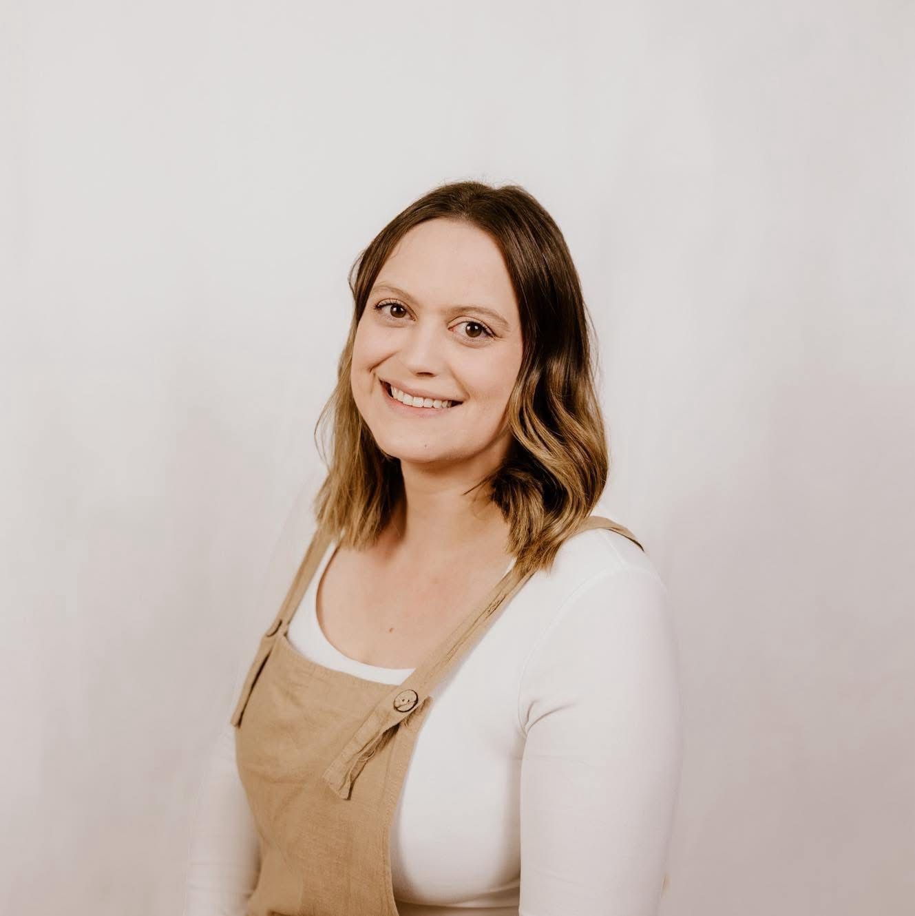 A woman wearing a black top and a floral jacket is smiling for the camera.