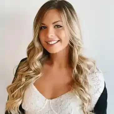 A woman with long blonde hair is wearing a white top and smiling.