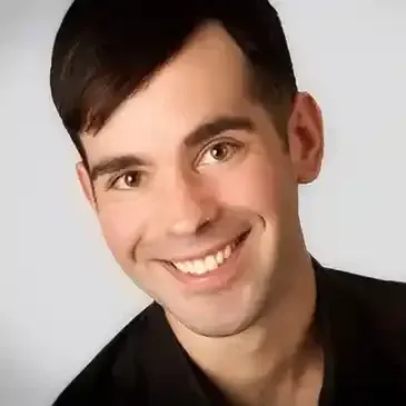 A young man in a black shirt is smiling for the camera.