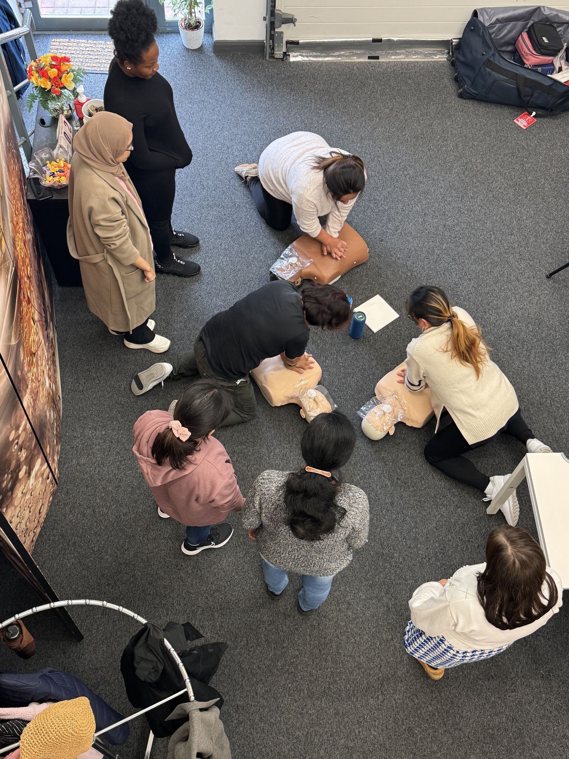 People practice CPR on mannequins in a classroom.