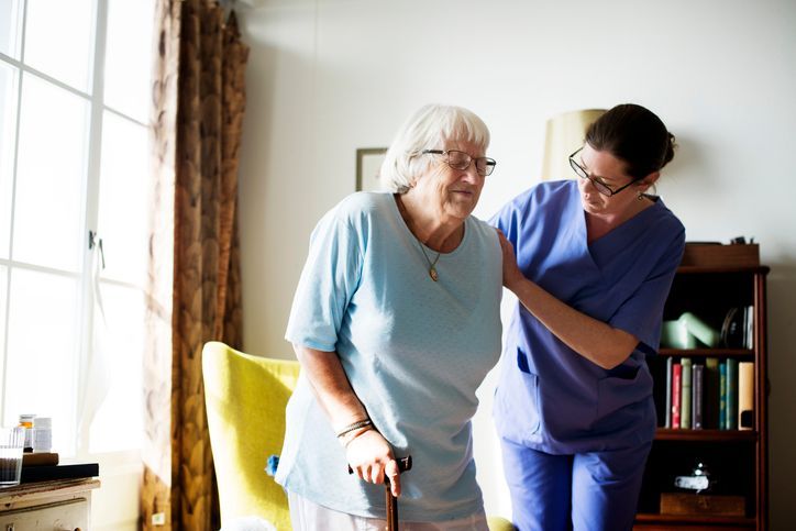 Carer helping senior woman to stand