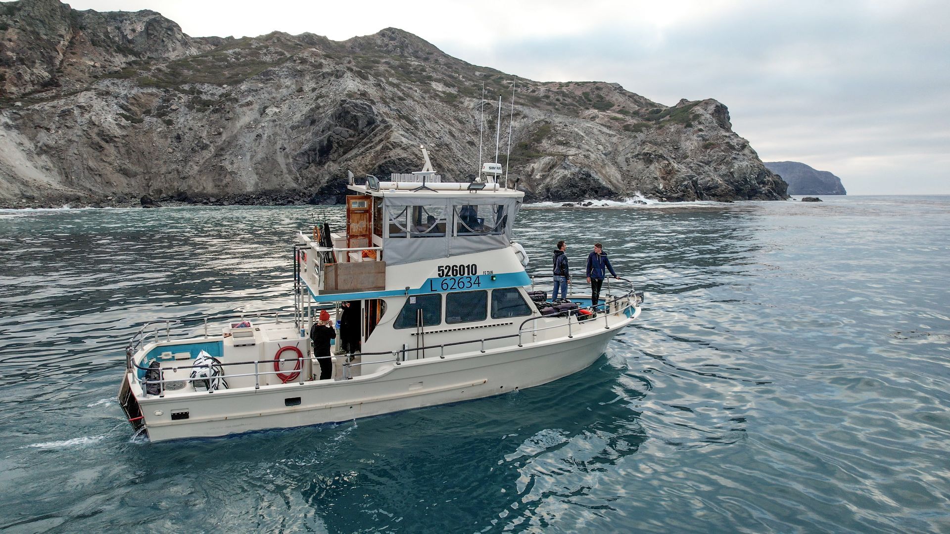 A boat is floating on a body of water with mountains in the background