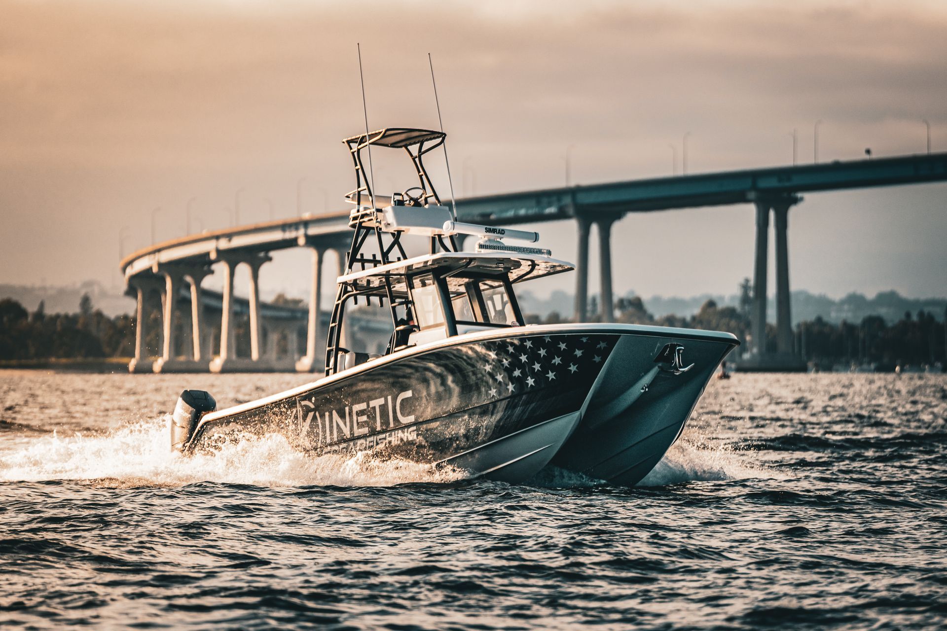 A boat is floating on top of a body of water under a bridge.