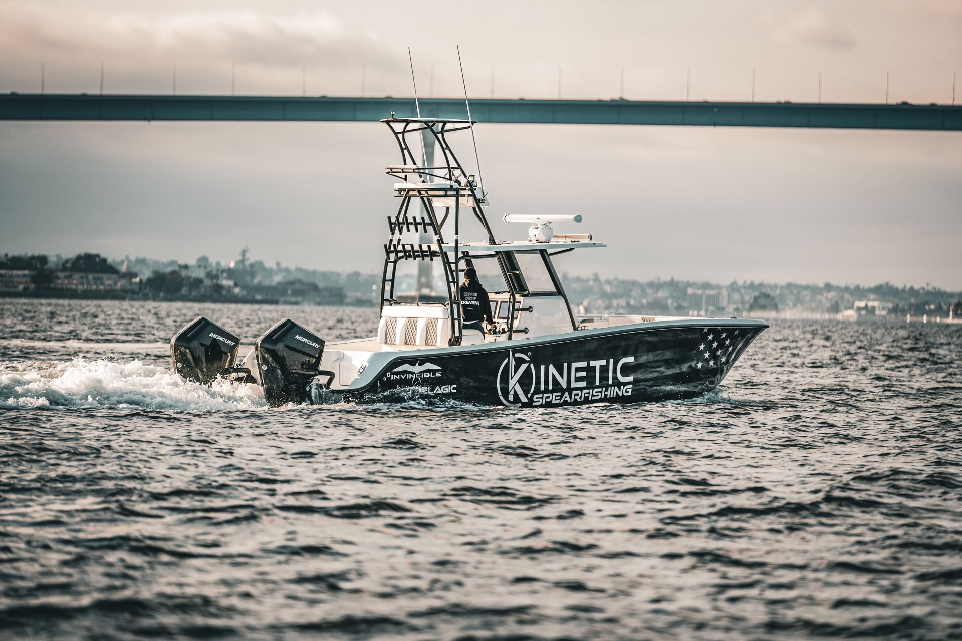 A boat is floating on top of a body of water under a bridge.