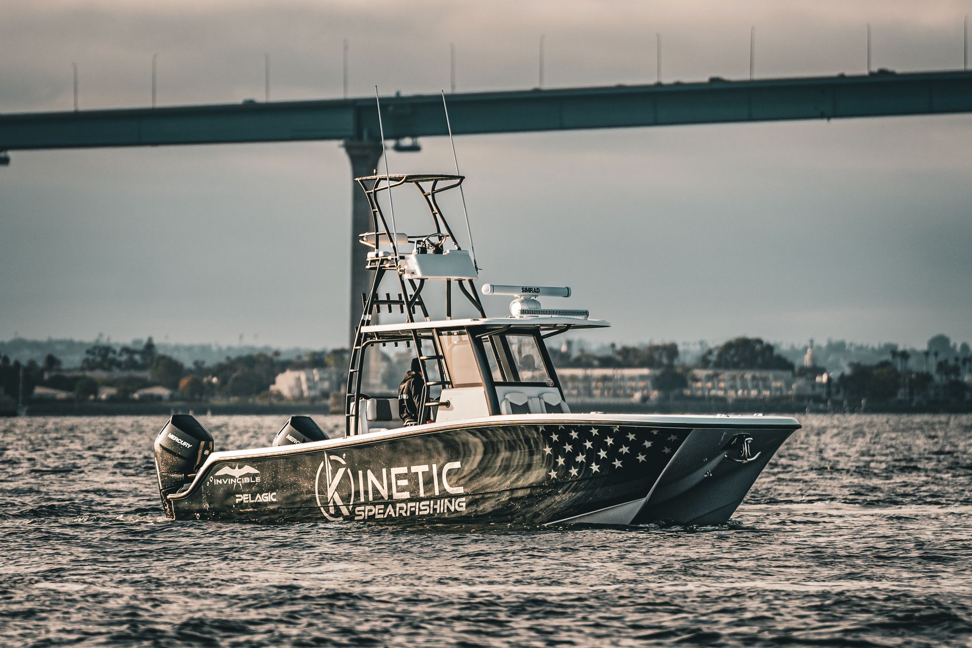 A boat is floating on top of a body of water under a bridge.