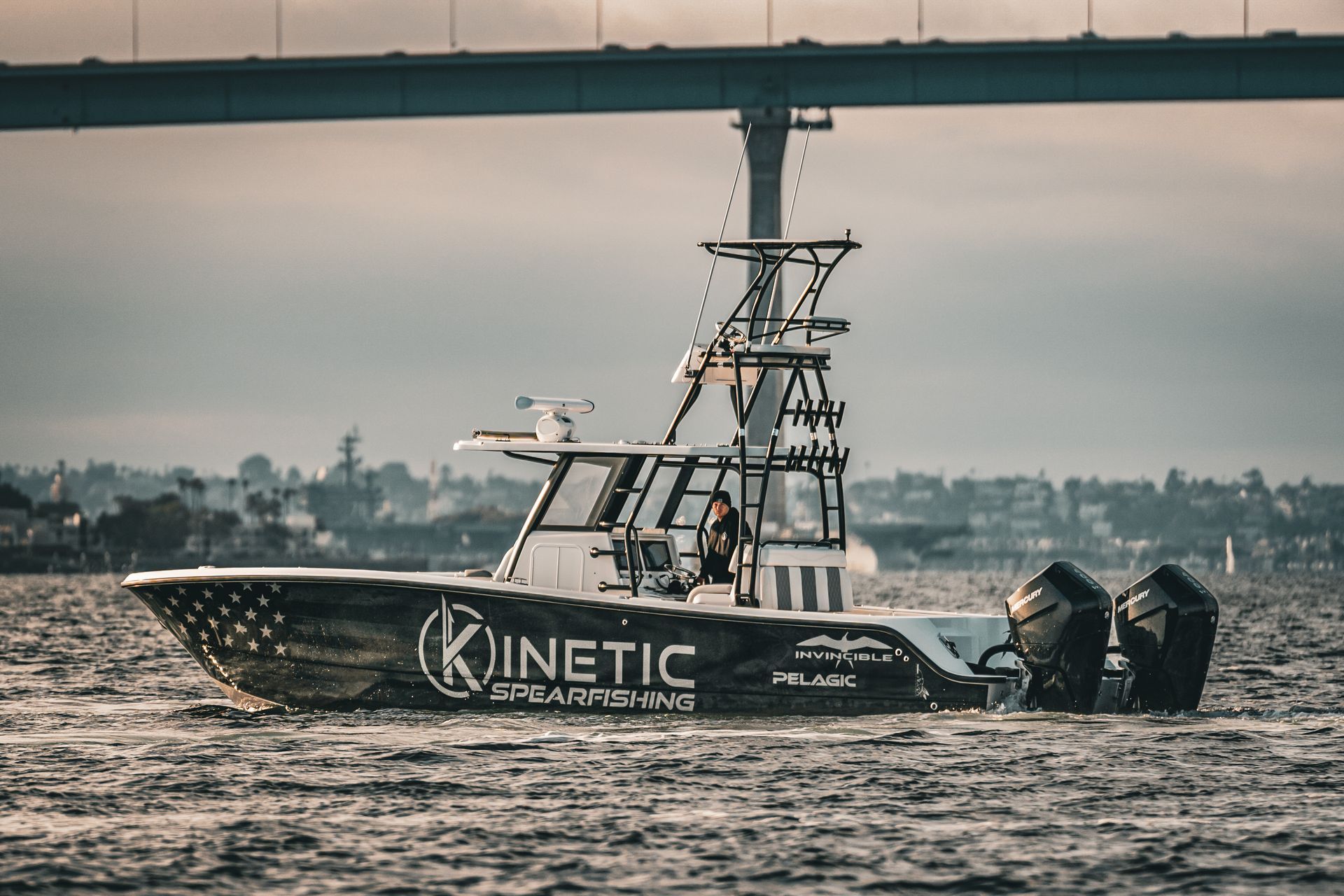 A boat is floating on top of a body of water under a bridge.