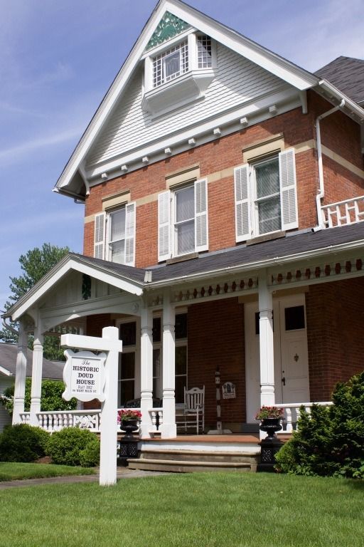 Brick house with white trim, porch, and open shutters;