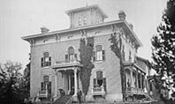 Historic brick Italianate style mansion with porch and tower.