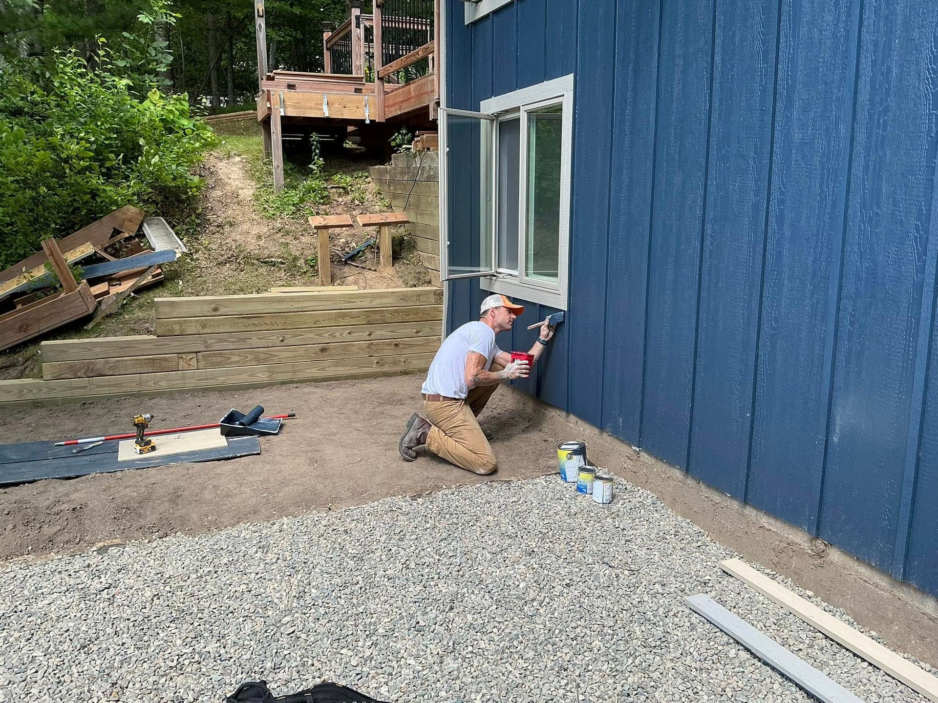 A man is kneeling down in front of a blue house.