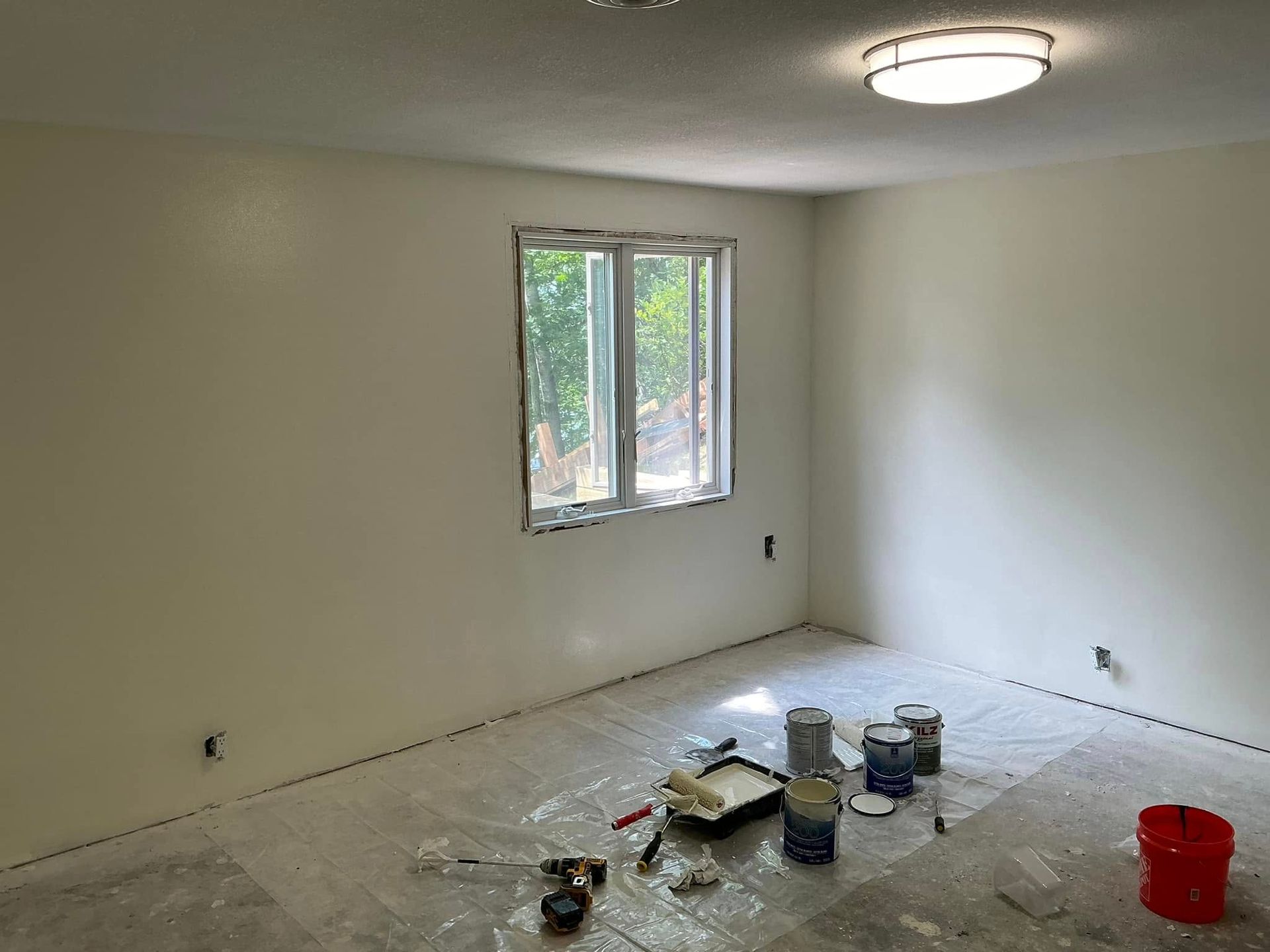 A room with white walls and a window is being painted.